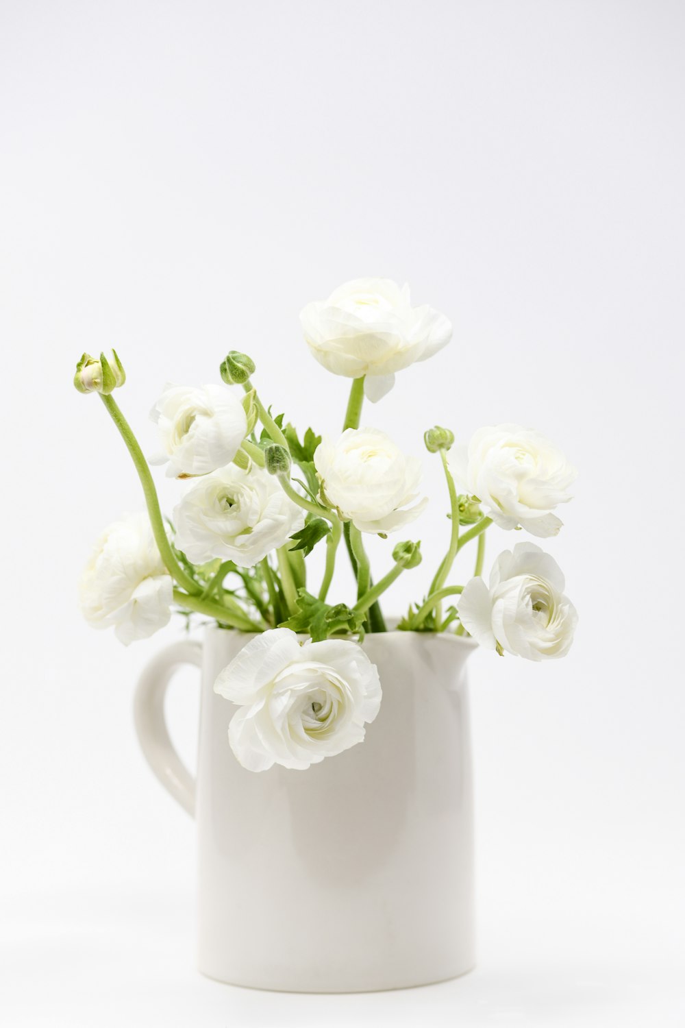 a white vase filled with white flowers on top of a table