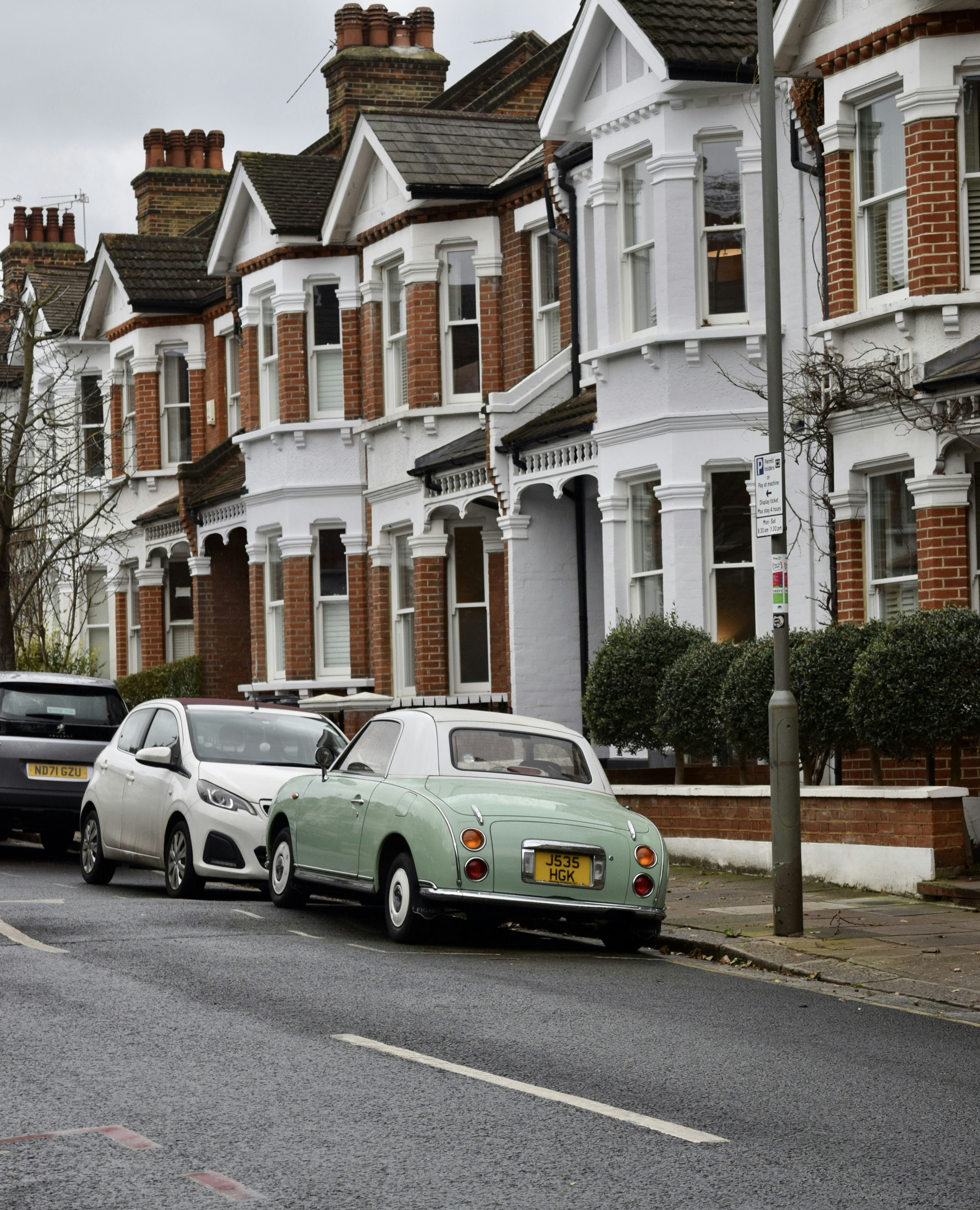 cars parked on the side of the road in front of a row of houses