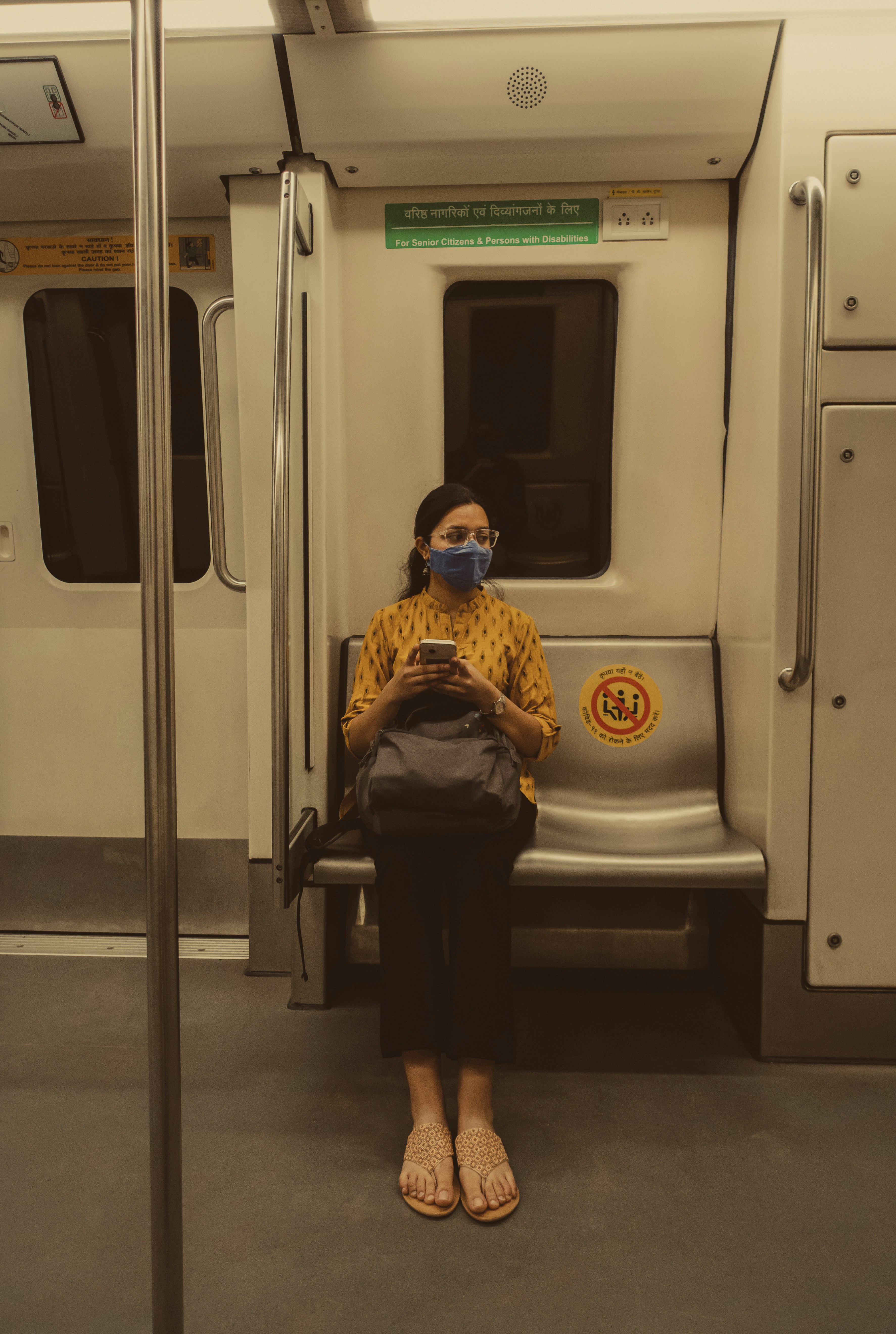 a woman sitting on a subway looking at her phone