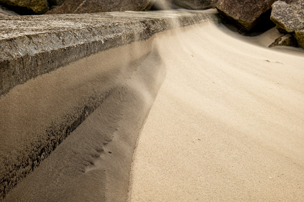 um banco de pedra sentado em cima de uma praia de areia