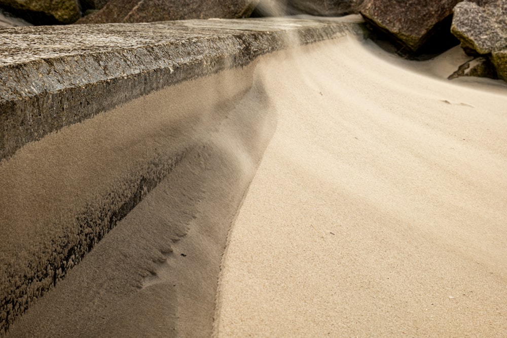 a stone bench sitting on top of a sandy beach