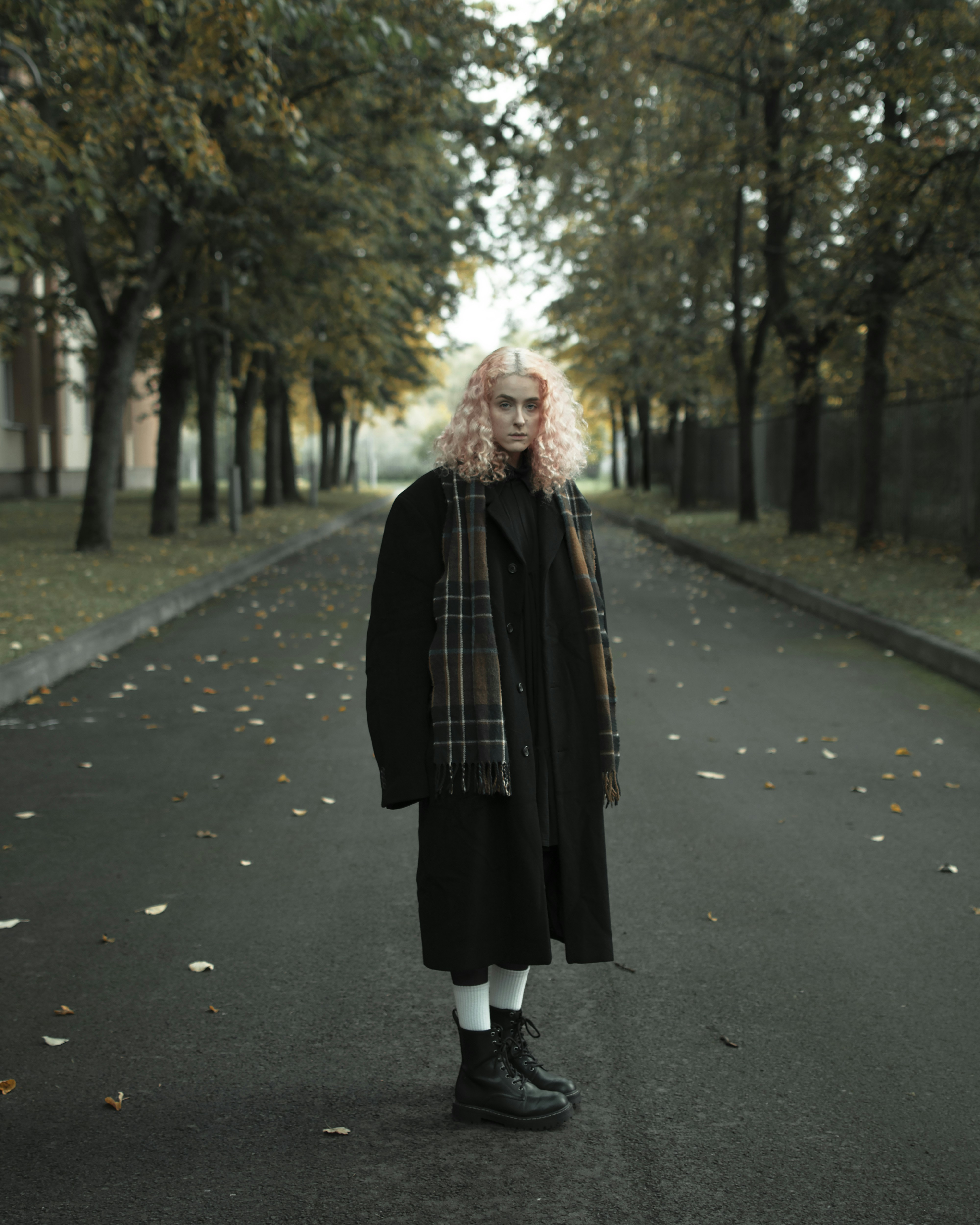 a woman with pink hair is standing in the middle of a road