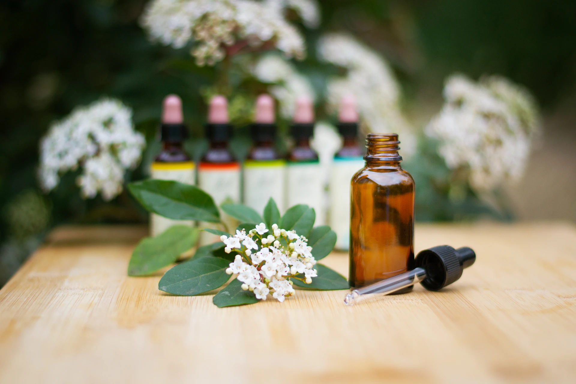 Botella de aceite esencial junto a flores frescas sobre mesa