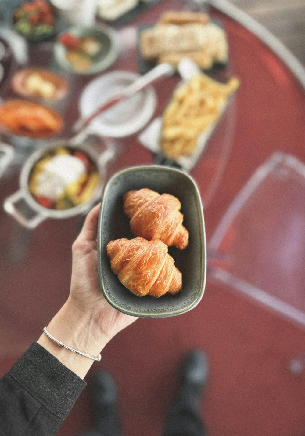 a person holding a bowl of food with croissants in it