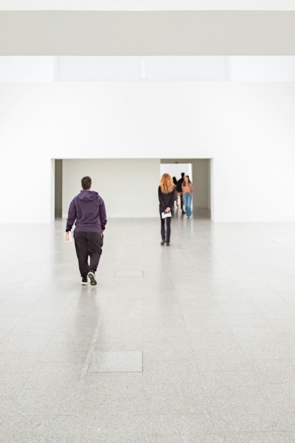 a group of people walking through a white room