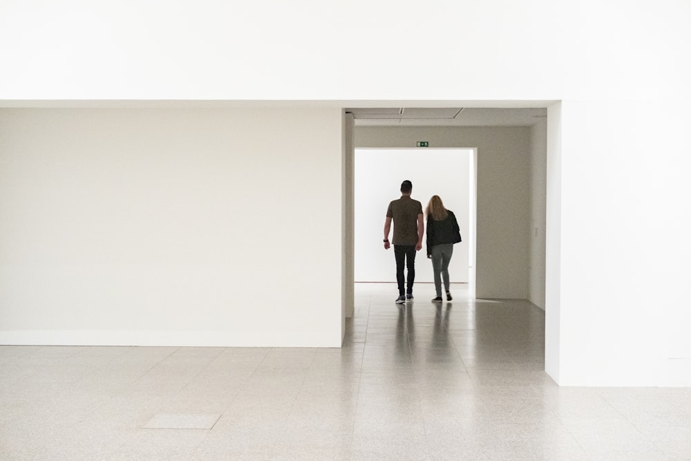 a man and a woman walking through a white room