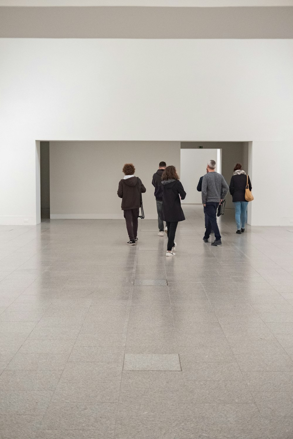 a group of people walking through a white room