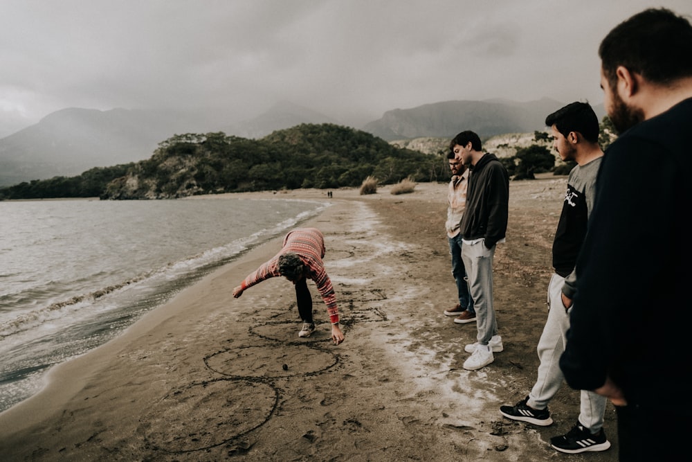 a group of men standing on top of a sandy beach