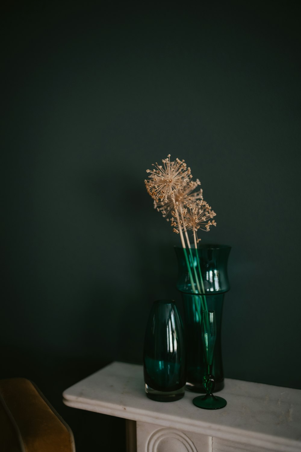two green vases with dried flowers on a table
