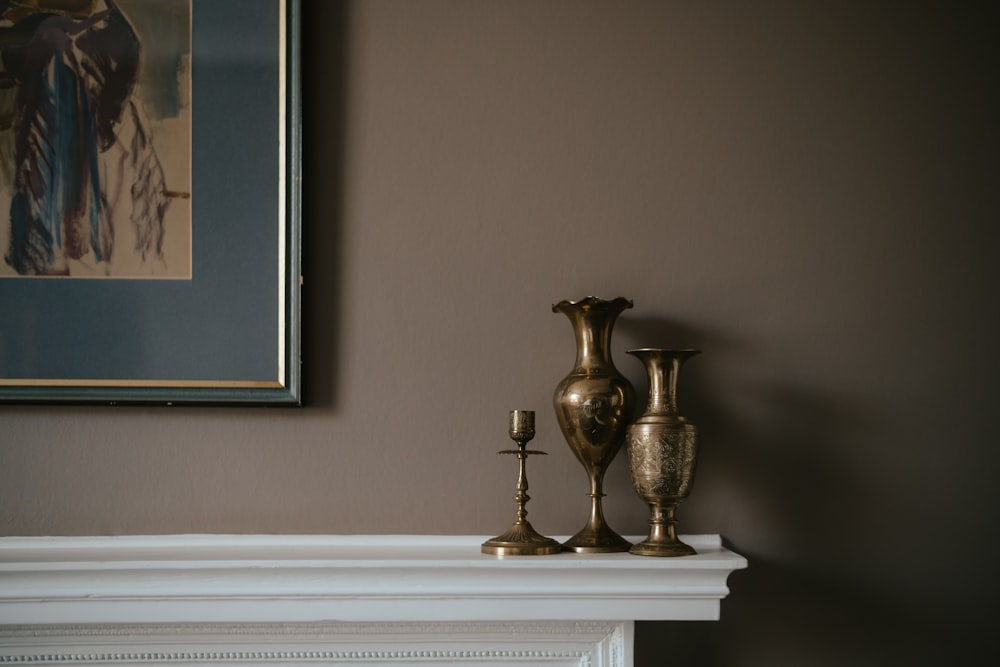 a couple of gold vases sitting on top of a mantle