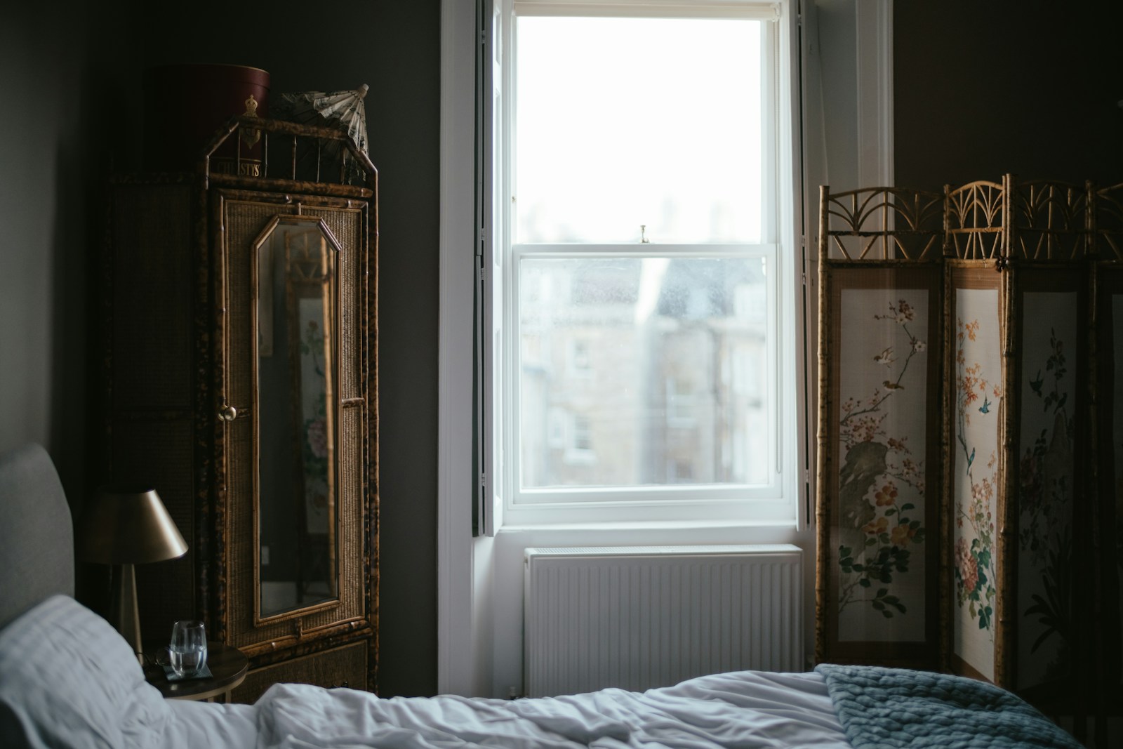 pre-war bedroom with folding screen and antique mirrored cabinet