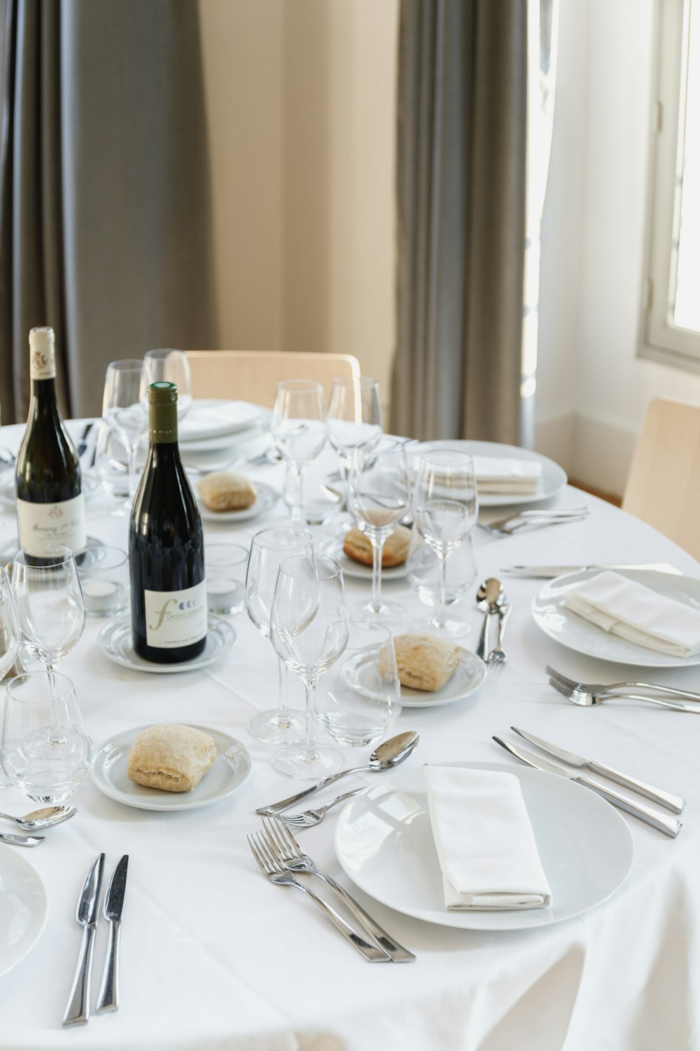a table set for a formal dinner with a bottle of wine