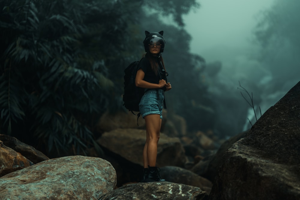 a woman standing on top of a large rock