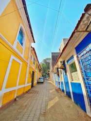 a narrow street with a yellow building and blue windows