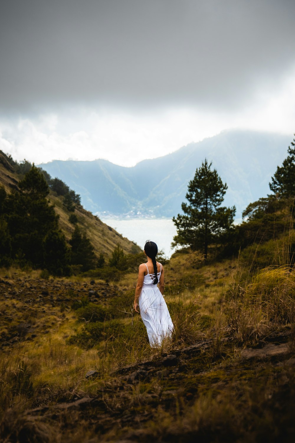 a woman in a white dress walking through a field