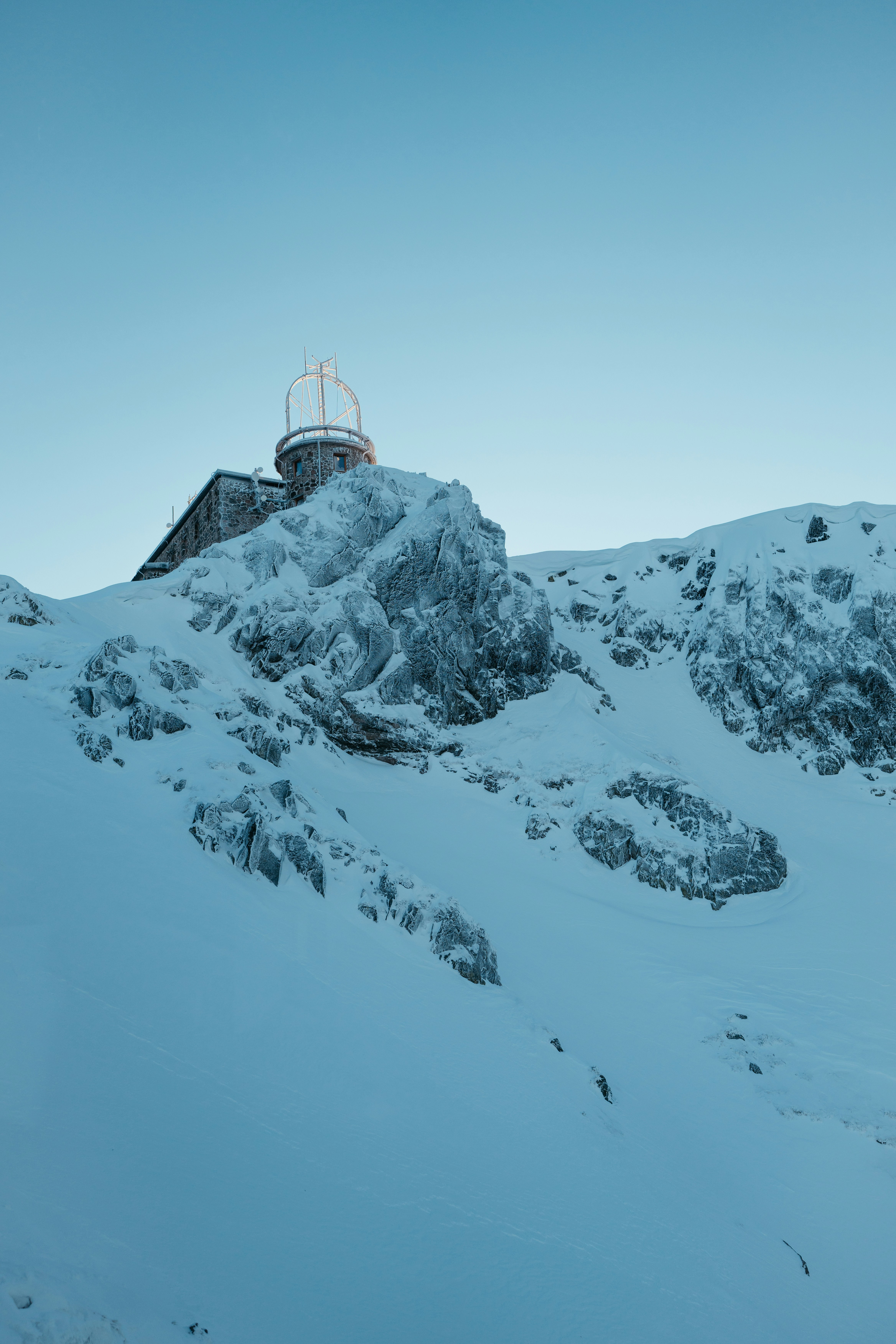 a mountain covered in snow with a ski lift in the distance