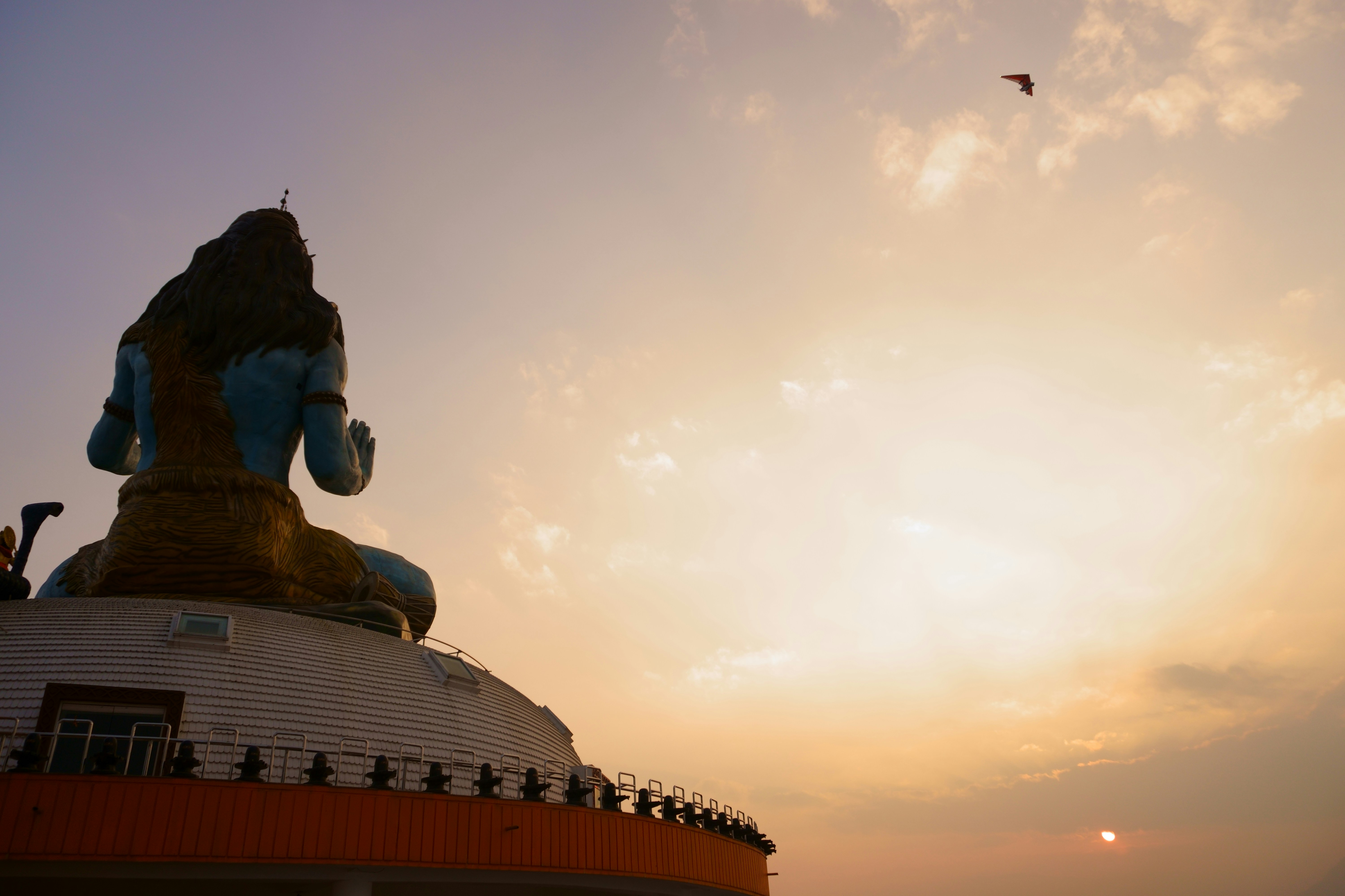a large statue sitting on top of a building under a cloudy sky