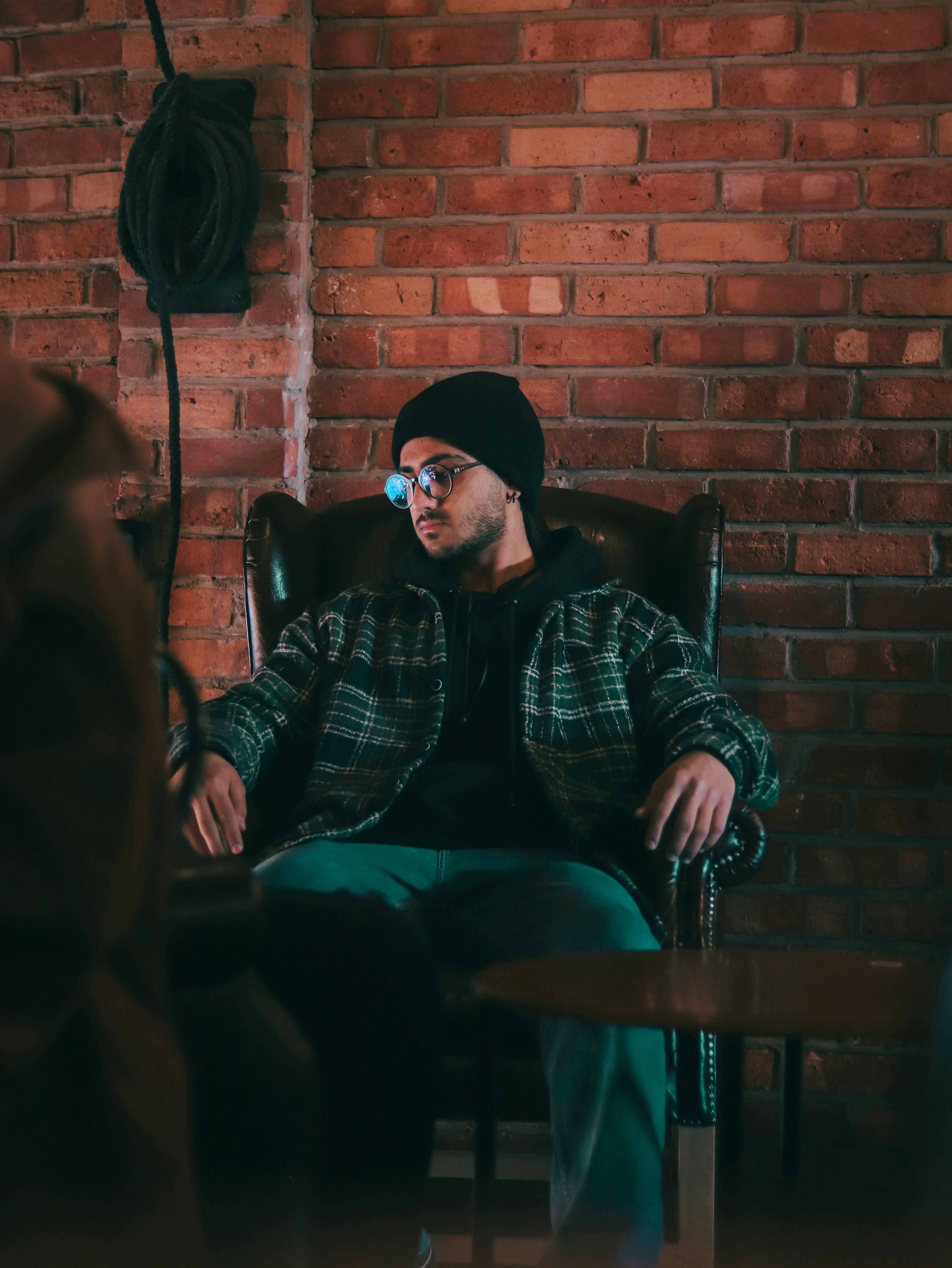 a man sitting in a chair in front of a brick wall
