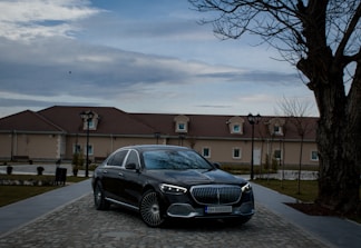 Black luxury car parked outside a formal event venue at dusk.