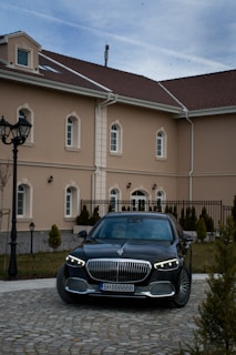 Luxury black sedan parked in front of a modern office building in Val-d'Oise.