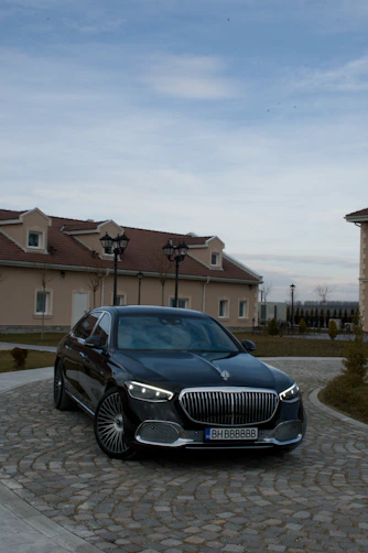 A sleek black car waiting outside Water Mill Airport terminal with a friendly driver holding a 'molavía' sign.