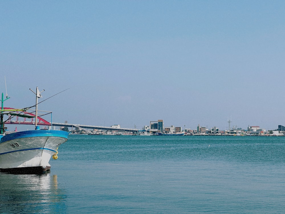 a blue and white boat floating on top of a body of water