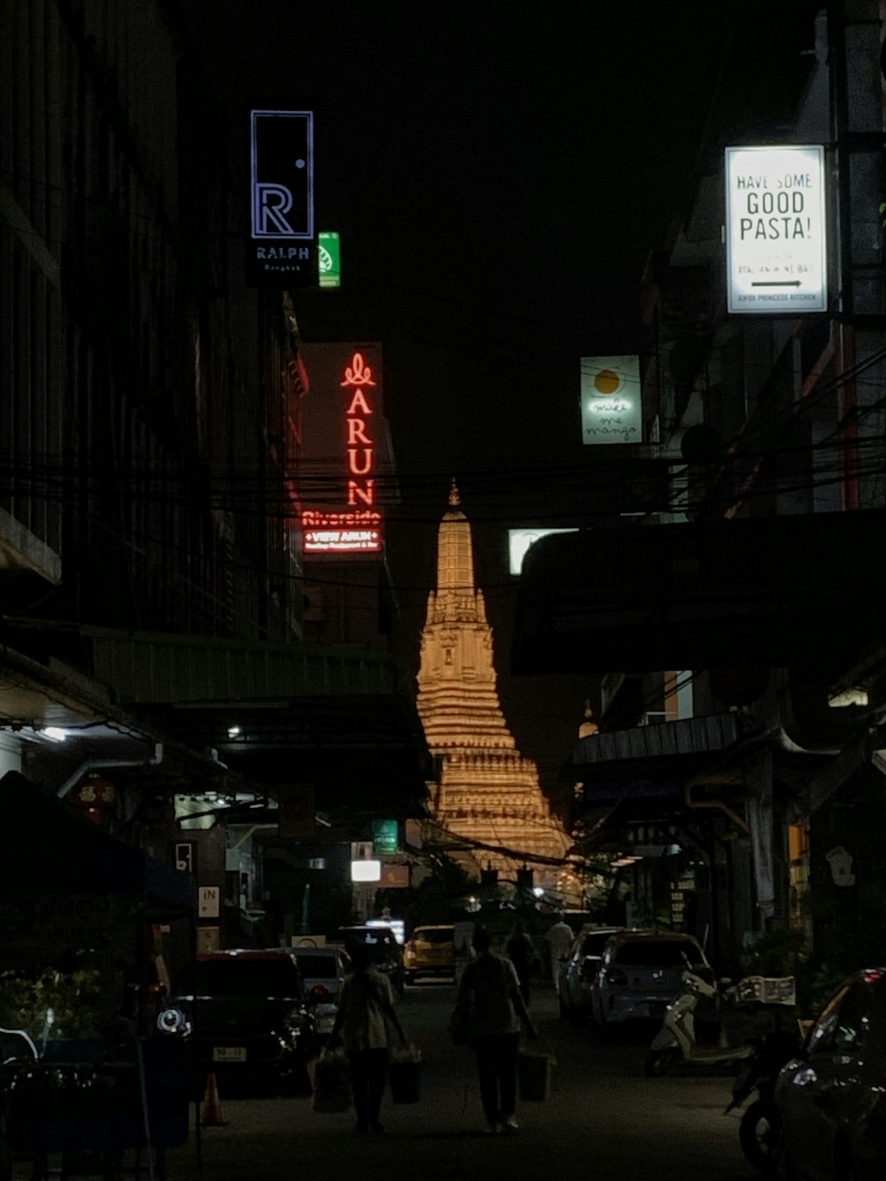 a city street at night with a lighted pagoda in the background