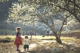 Children walking along a forest trail, holding hands and observing the surroundings attentively.