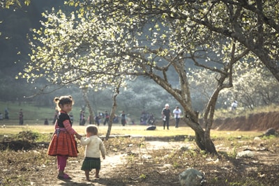 Children walking along a forest trail, holding hands and observing the surroundings attentively.