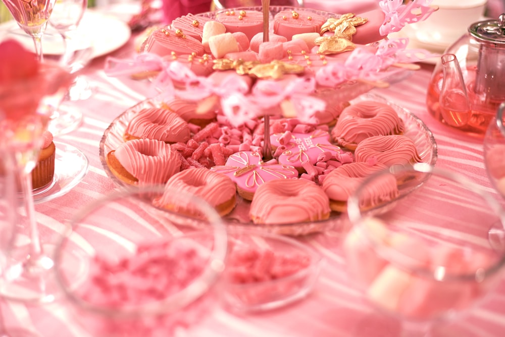 Una mesa cubierta con muchos postres rosados