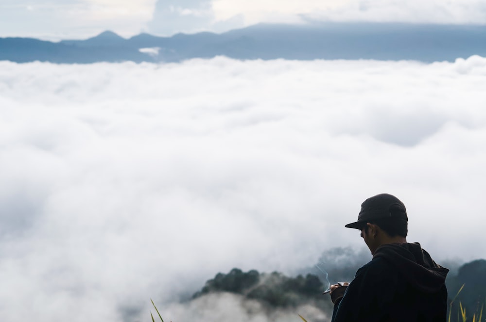 a man standing on top of a mountain above the clouds