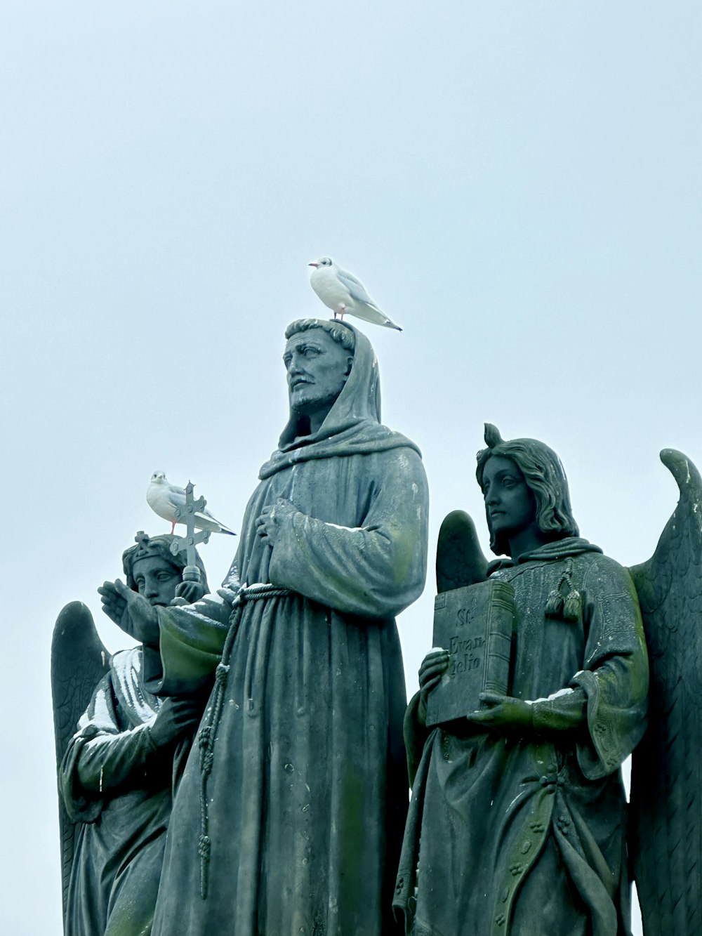 a statue of a man and two angels with a bird on his shoulder