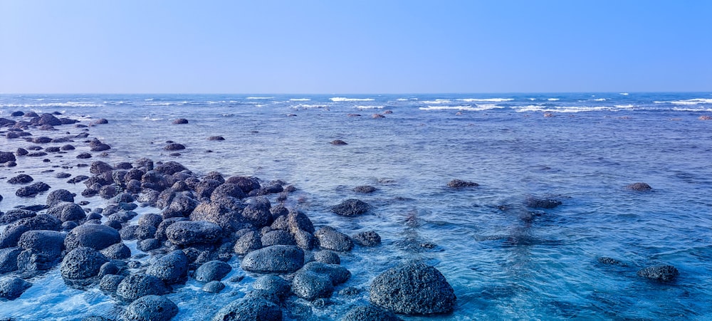 a rocky beach with blue water and rocks