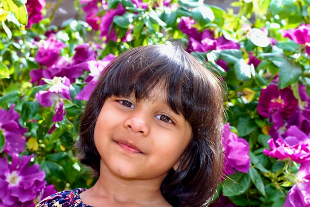 Close-up of a joyful child holding a flower, captured with soft natural light.