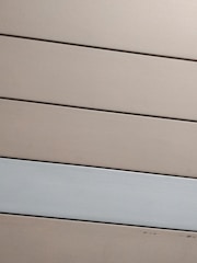 Horizontal panels with a matte finish are arranged in parallel. The panels are mostly beige with one grayish-white panel standing out against the rest.