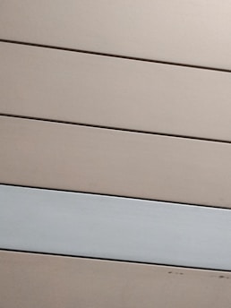 Horizontal panels with a matte finish are arranged in parallel. The panels are mostly beige with one grayish-white panel standing out against the rest.