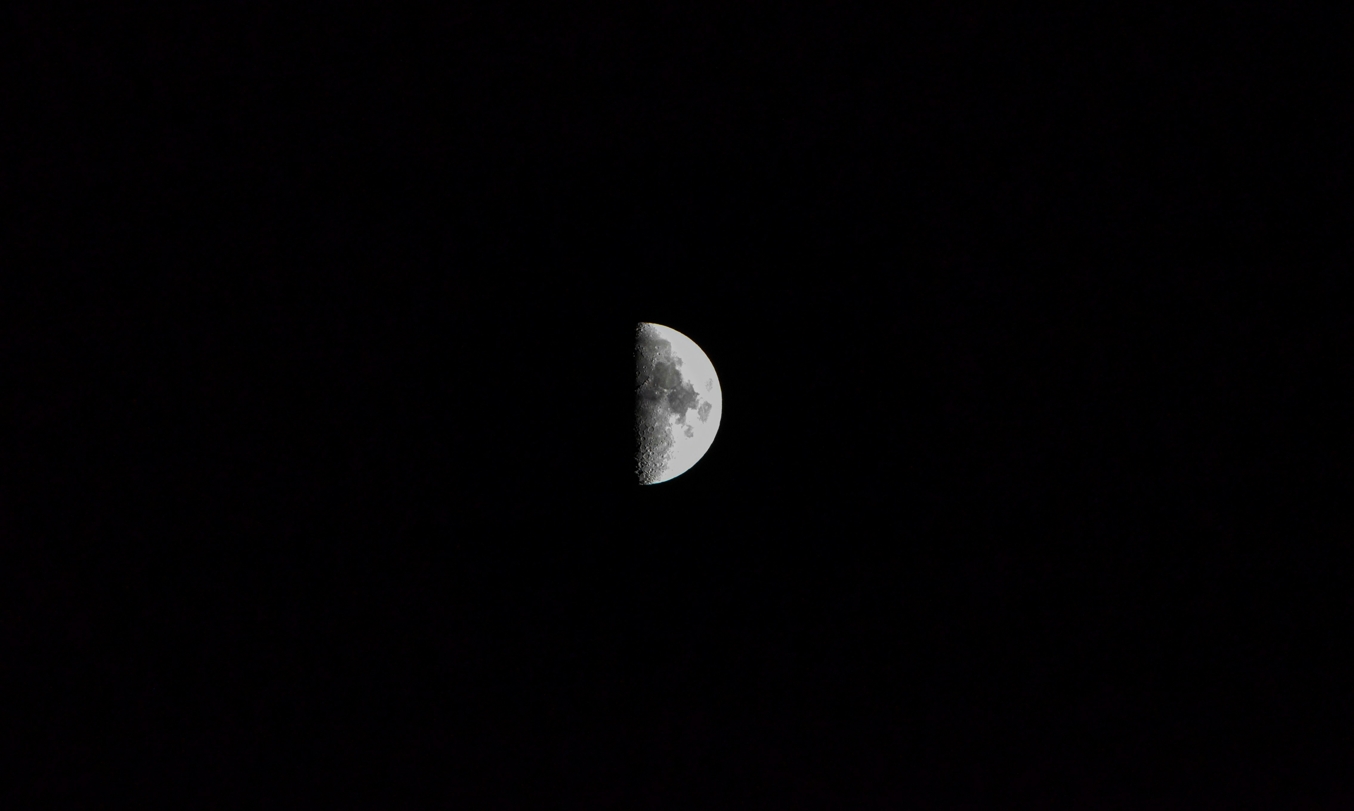 a half moon is seen in the dark sky