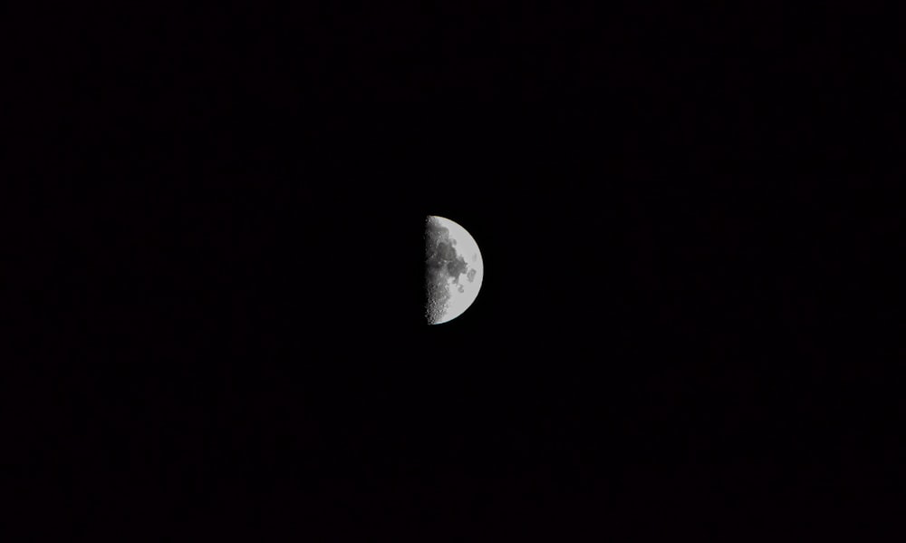 a half moon is seen in the dark sky