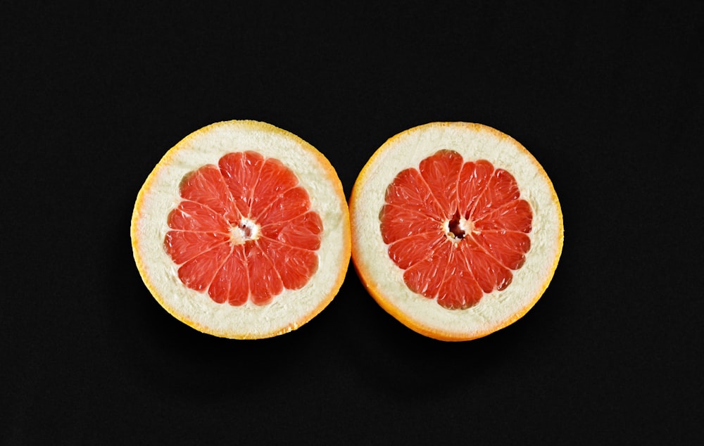 a grapefruit cut in half on a black background