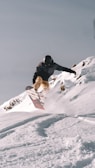 a man riding a snowboard down the side of a snow covered slope