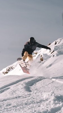 a man riding a snowboard down the side of a snow covered slope