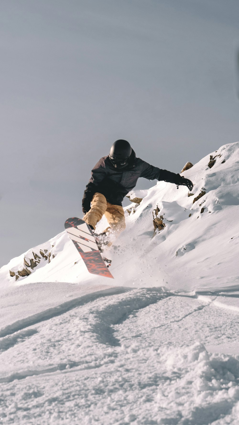 a man riding a snowboard down the side of a snow covered slope