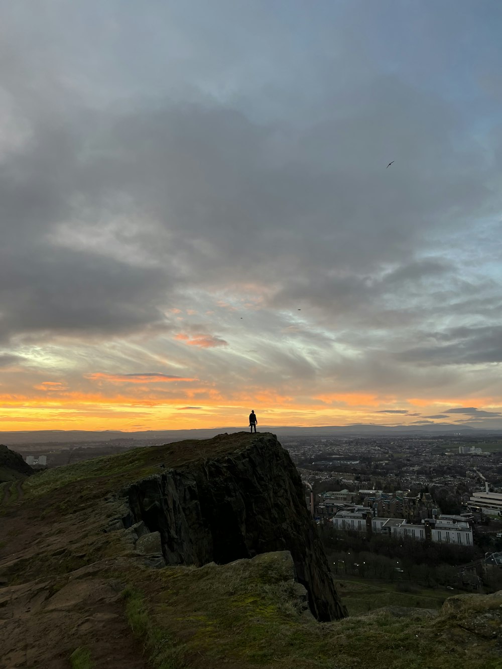 uma pessoa em pé no topo de uma colina com vista para uma cidade