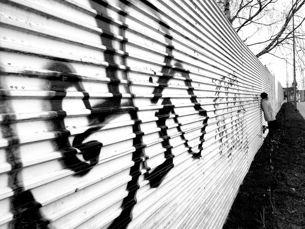 a black and white photo of a person standing next to a wall