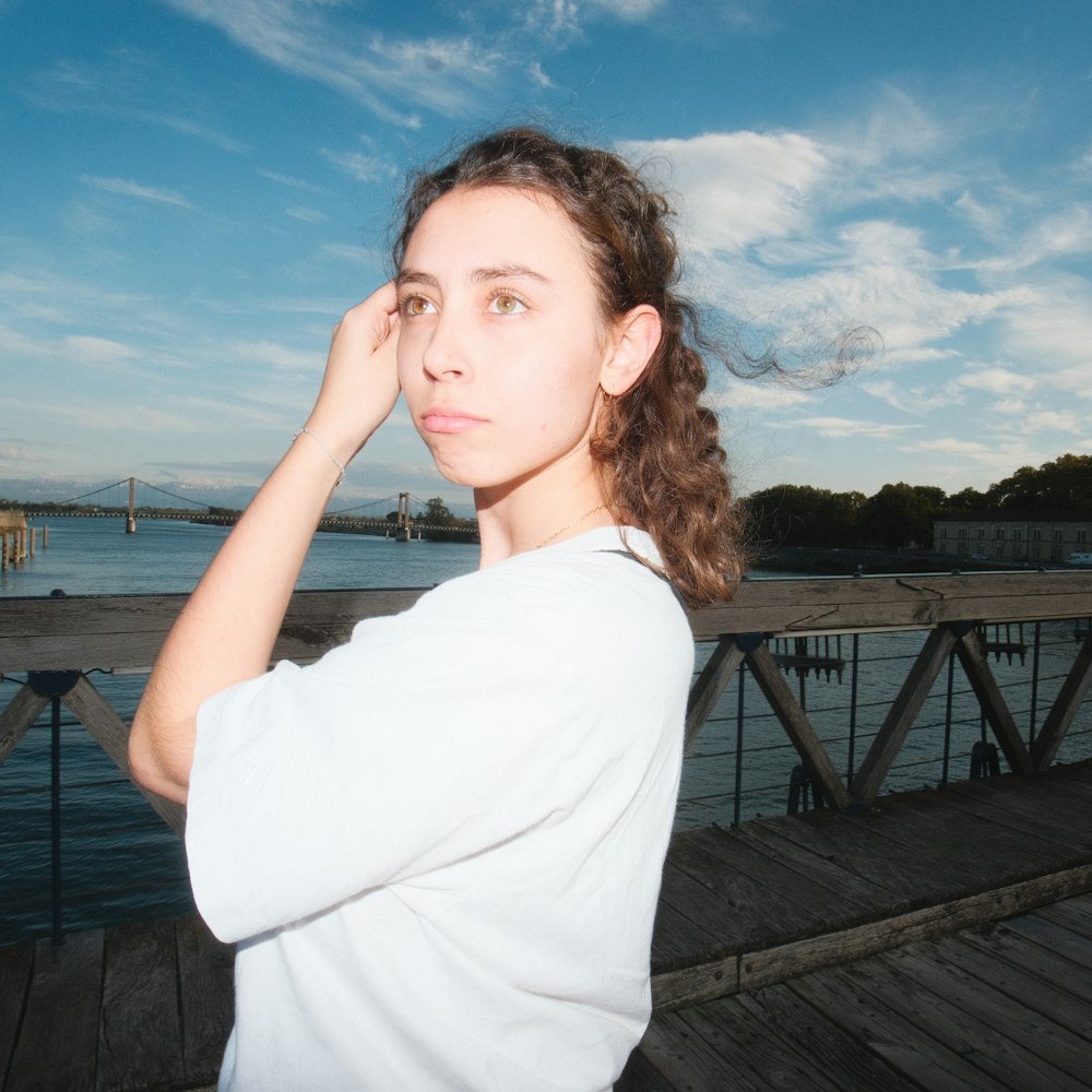 a woman standing on a pier with her hand on her head