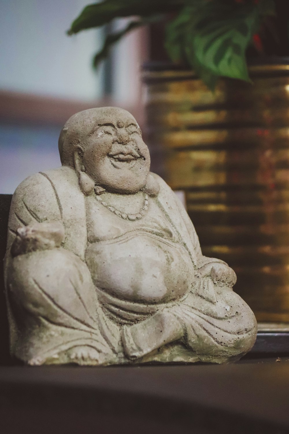 a buddha statue sitting next to a potted plant