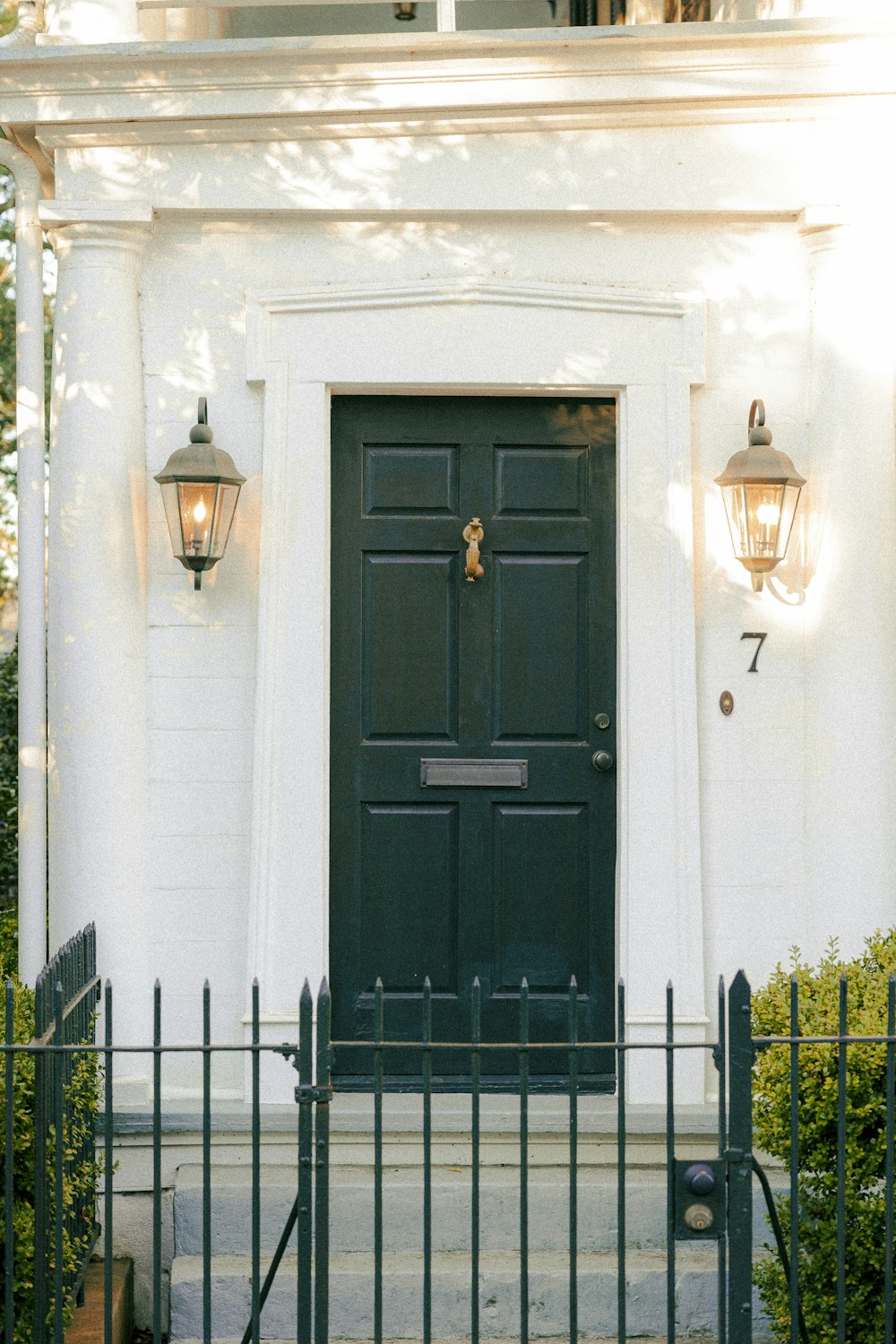 a black front door with two lights on the side of it
