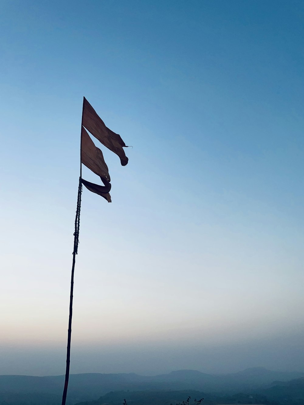 a flag on top of a pole with a sky in the background