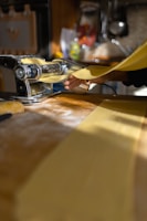 Close-up of a chef preparing fresh pasta by hand in a traditional kitchen.