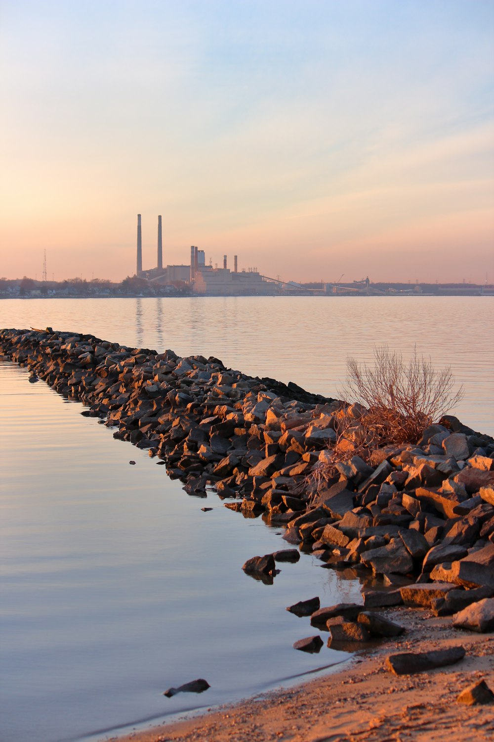 a large body of water with a factory in the background